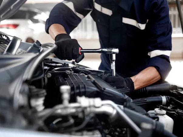 Mécanicien en gants noirs réparant un moteur de voiture avec une clé à cliquet à Saint-Gilles dans le Gard 30