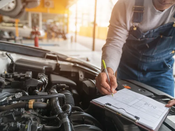 Mécanicien vérifiant un moteur de voiture, notant des informations sur un presse-papiers à Saint-Gilles dans le Gard 30